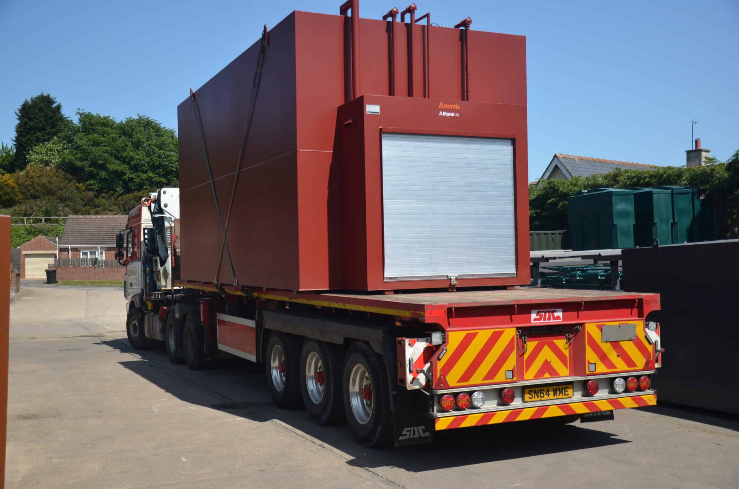 Large red steel tank with silver door on the back of a lorry.