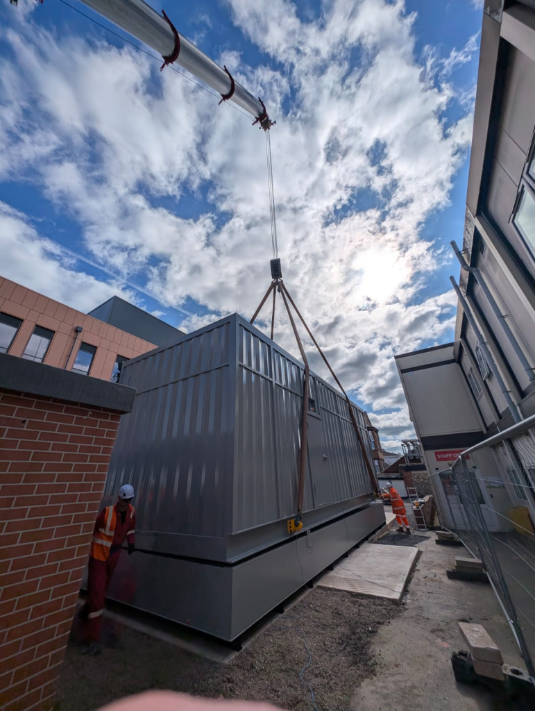 Generator enclosure being positioned above a structural slab fuel tank at Warwick Hospital.